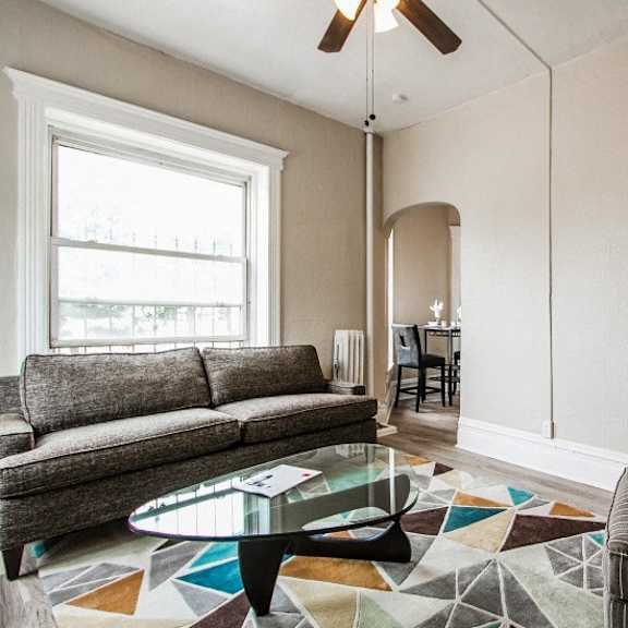 a living room with a grey couch, a glass coffee table, and a striped armchair.