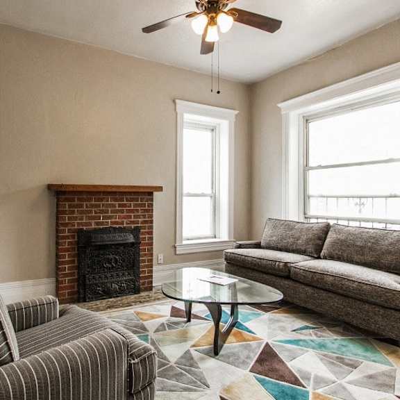 a living room with a fireplace, a striped chair, a coffee table, and a couch.