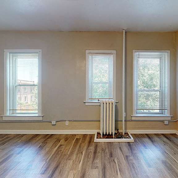 a room with wooden floors and two windows.