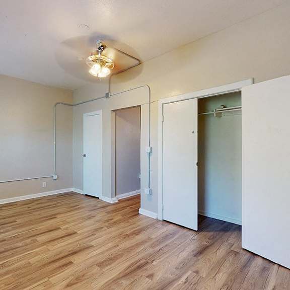 a room with a white ceiling, wooden floor, and white walls with a window on the left side.
