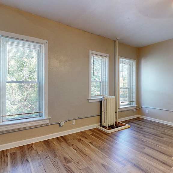 a room with wooden floors and two windows.