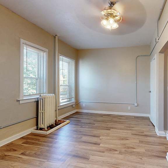 a room with wooden floors and a window with a radiator beneath it.