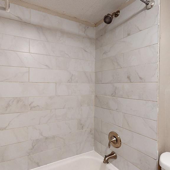 a white bathroom with a marble tile wall.