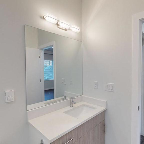 a bathroom with a sink, mirror, and lighting fixture.