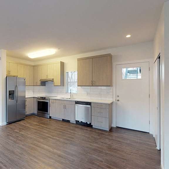 a kitchen with wooden floors and white walls.