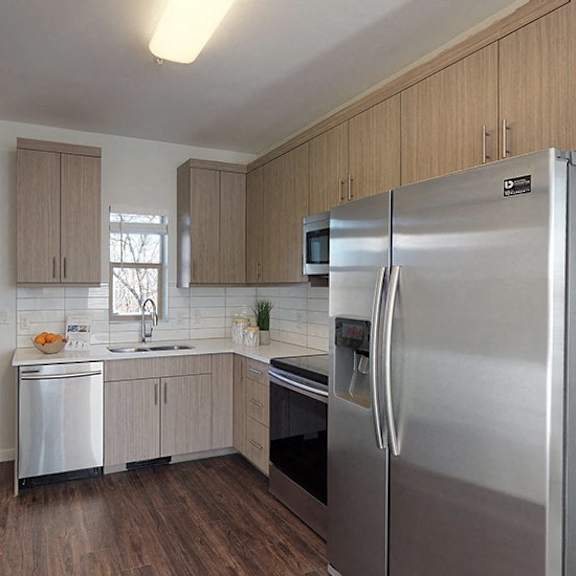 a kitchen with a refrigerator, sink, and cabinets.
