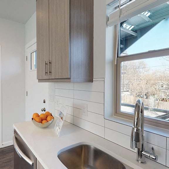 a kitchen with a white counter top and a stainless steel sink.
