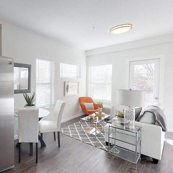 a modern kitchen with a refrigerator, oven, and a dining table with chairs.