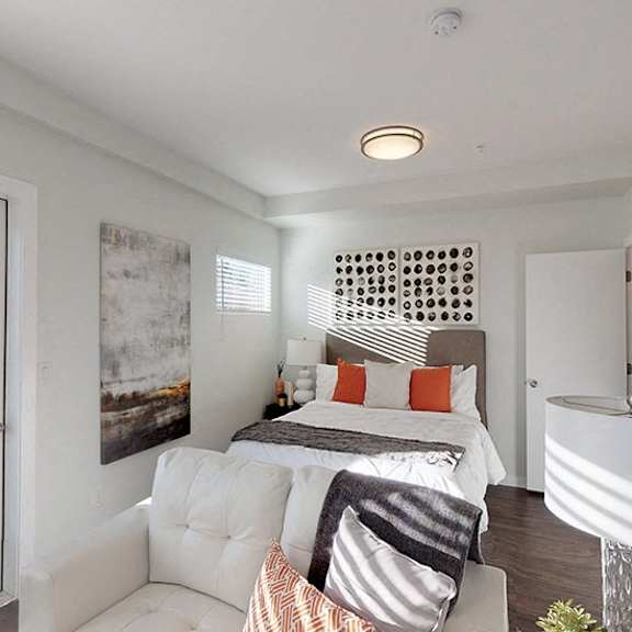 a bedroom with a bed, a couch, and a painting on the wall.