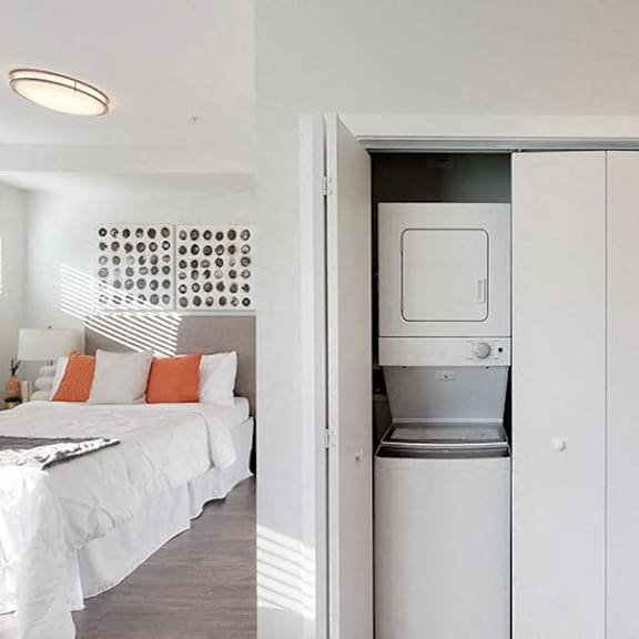 a white bedroom with a washing machine in the closet.