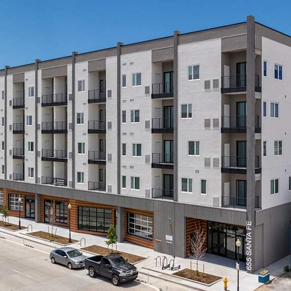 a modern apartment building with a parking lot in front.
