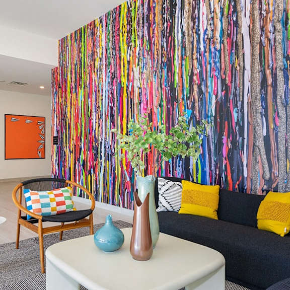 a room with a couch, a table, and a wall covered in colorful art.