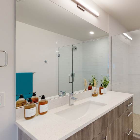 a modern bathroom with a white sink and a glass shower door.