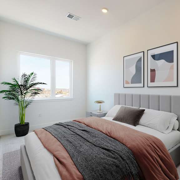 a bedroom with a bed, nightstand, and a plant.