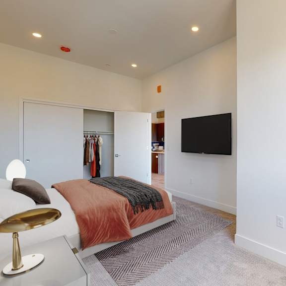 a bedroom with a bed, a chair, a plant and a television.