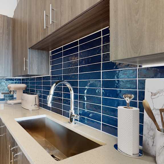 a modern kitchen with a stainless steel oven and a blue tile backsplash.