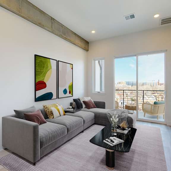 a living room with a grey couch and a painting on the wall.