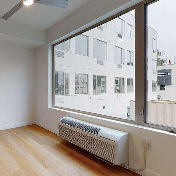 a room with a window and a wall-mounted air conditioner.