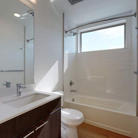 a white sink with a brown cabinet and a white toilet in a bathroom.