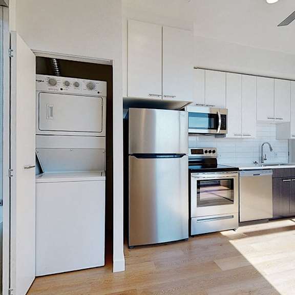 a modern kitchen with stainless steel appliances and white cabinetry.