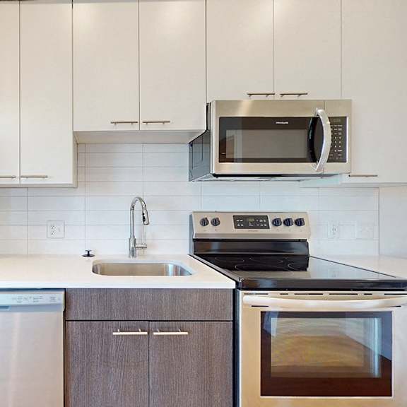 a modern kitchen with white cabinets and stainless steel appliances.