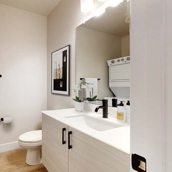 a white bathroom with a toilet, sink, and a white towel hanging on the wall.