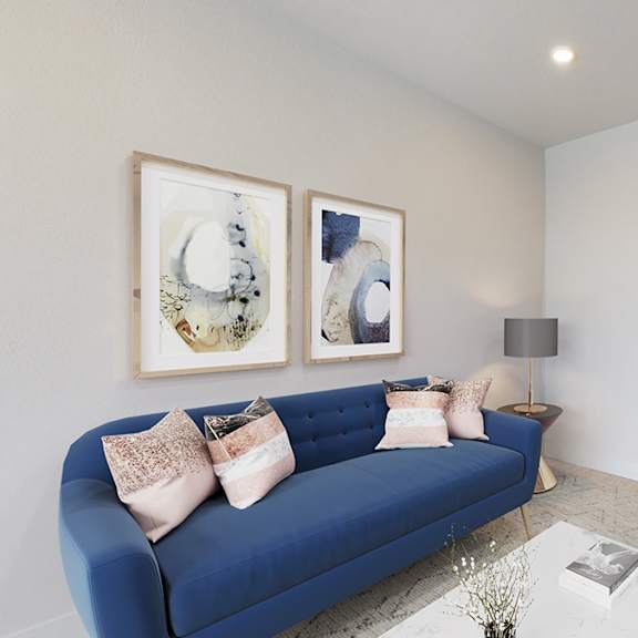 a blue couch with two pillows sits in a living room with a white coffee table in front of it.