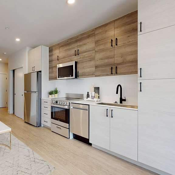 a modern kitchen with a blue couch and wooden cabinets.
