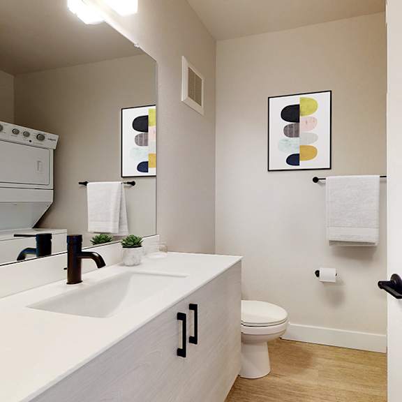a white bathroom with a toilet, sink, and mirror.