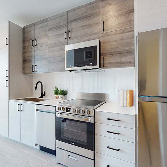 a modern kitchen with a stainless steel refrigerator, a microwave above the oven, and white cabinets.