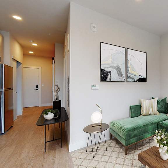 a living room with a green couch and a painting on the wall.