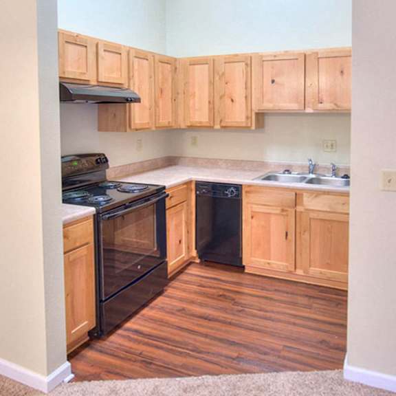 a kitchen with wooden cabinets and a black dishwasher.