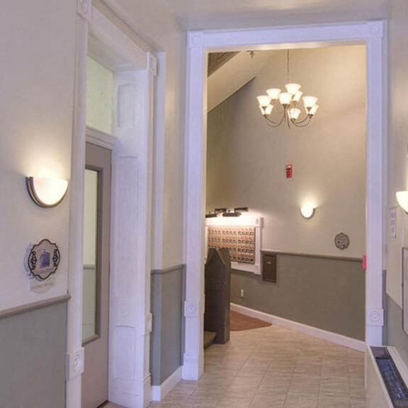 a hallway with a chandelier and framed pictures on the wall.