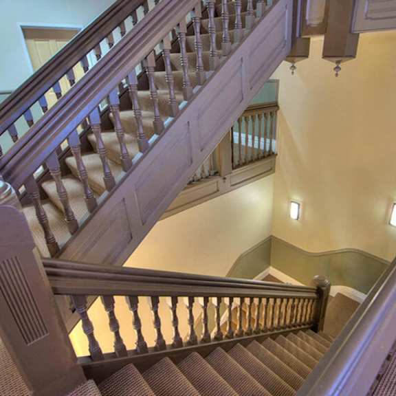a staircase with a wooden handrail and a carpeted floor.