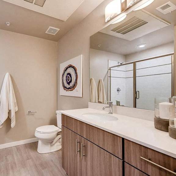 a bathroom with a toilet, sink, mirror, and towel rack.