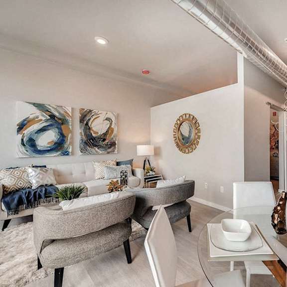 a modern living room with a grey sofa, a white coffee table, and a white dining table.