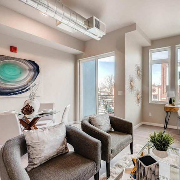 a living room with a grey couch, a chair, a coffee table, and a large window.