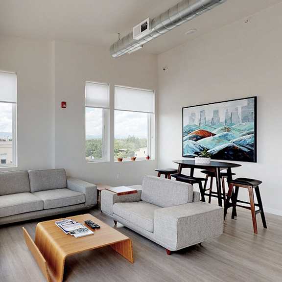 a living room with a grey couch, a wooden coffee table, and a painting on the wall.