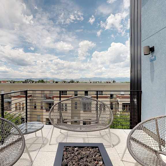 a balcony with a table and chairs overlooking a cityscape.