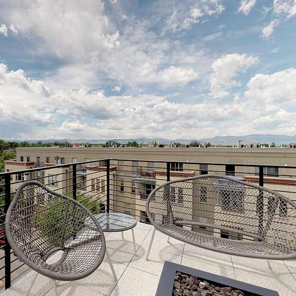 a balcony with a table and chairs overlooking a parking lot.