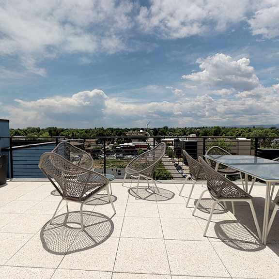 a patio with chairs and tables overlooking a landscape.