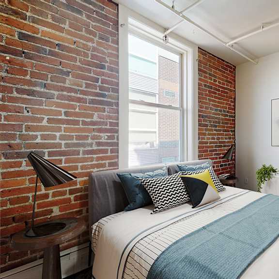 a bedroom with a bed, pillows, a lamp, and a painting on the wall.