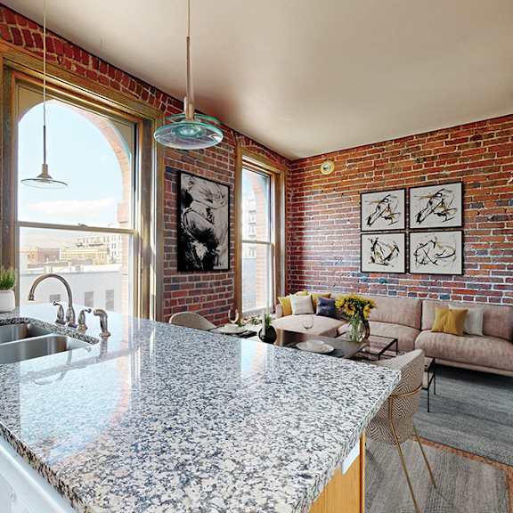 a kitchen with a granite countertop and a brick wall.