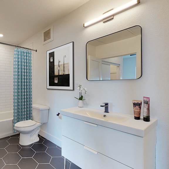 a bathroom with a white toilet, sink, and mirror.