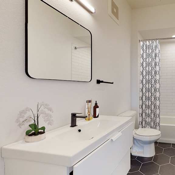 a white bathroom with a toilet, sink, and a mirror.