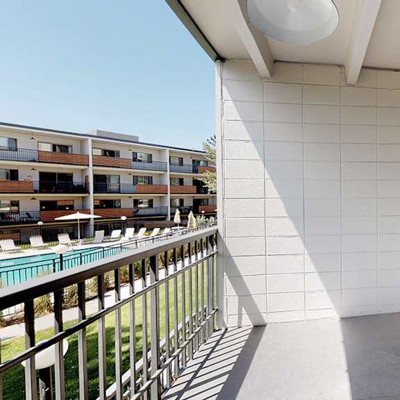 a balcony with a white wall and a glass door.