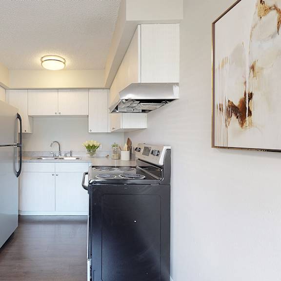 a black refrigerator stands in a kitchen with white cabinets and a black dishwasher.