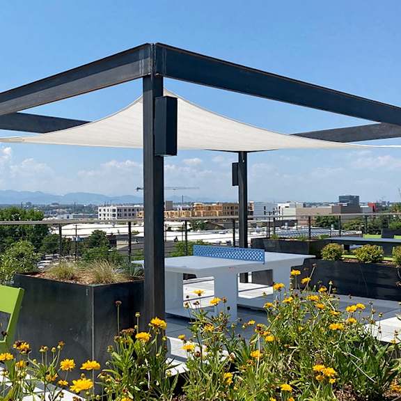 a patio with a white canopy and green chairs overlooking a cityscape.