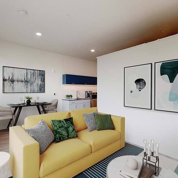 a living room with a yellow couch and two framed pictures on the wall.