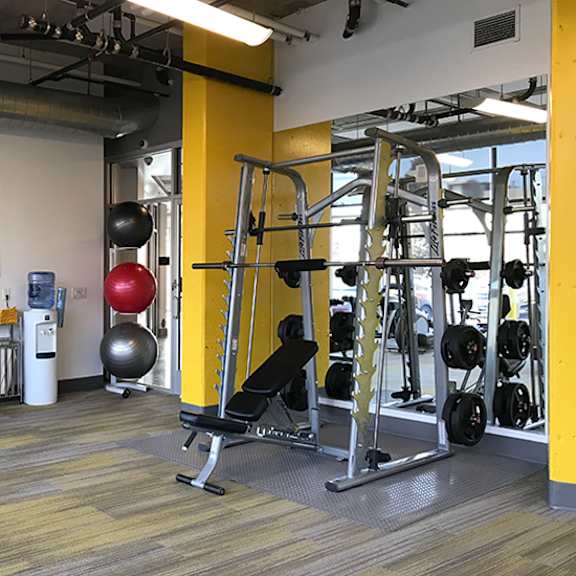 a gym with a variety of equipment including a weight bench, a rowing machine, and a television.